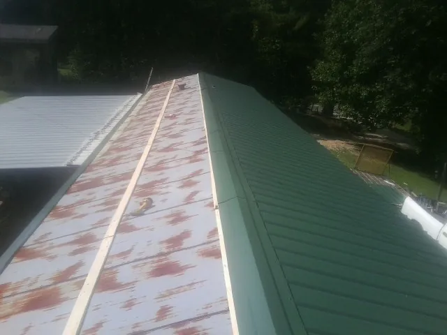 Old rusted panels beside newly installed green metal roofing — Wind Damage Roof Repair by Roofing Brothers in Morse