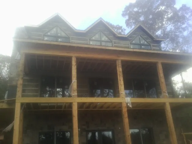 Dormers and porch framing on a large log home under construction — Roof Coating work by our crew in Morse