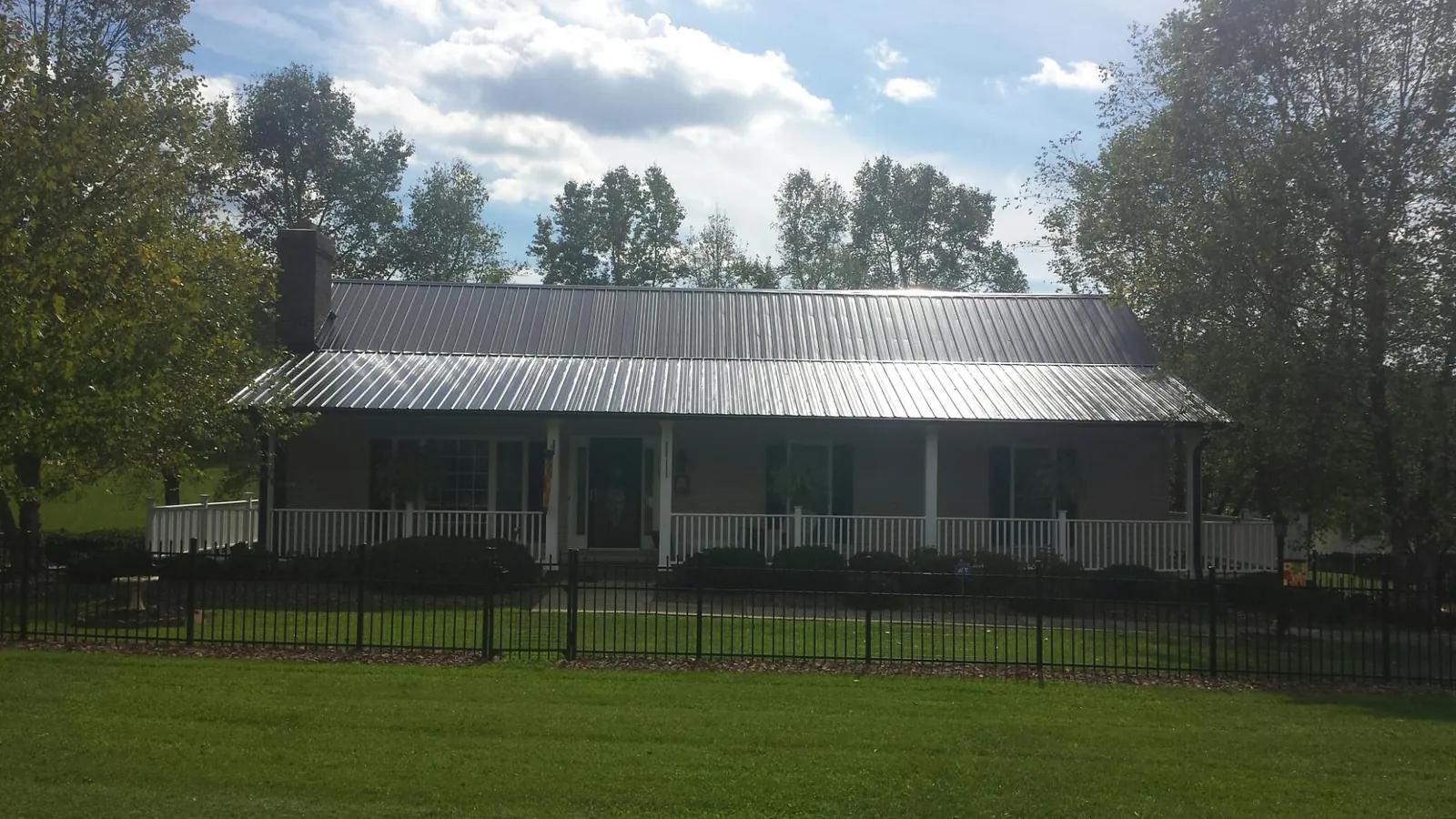 Gray metal roof on a brick ranch with a full width front porch — Gutter Guard Installation work by our crew in Morse
