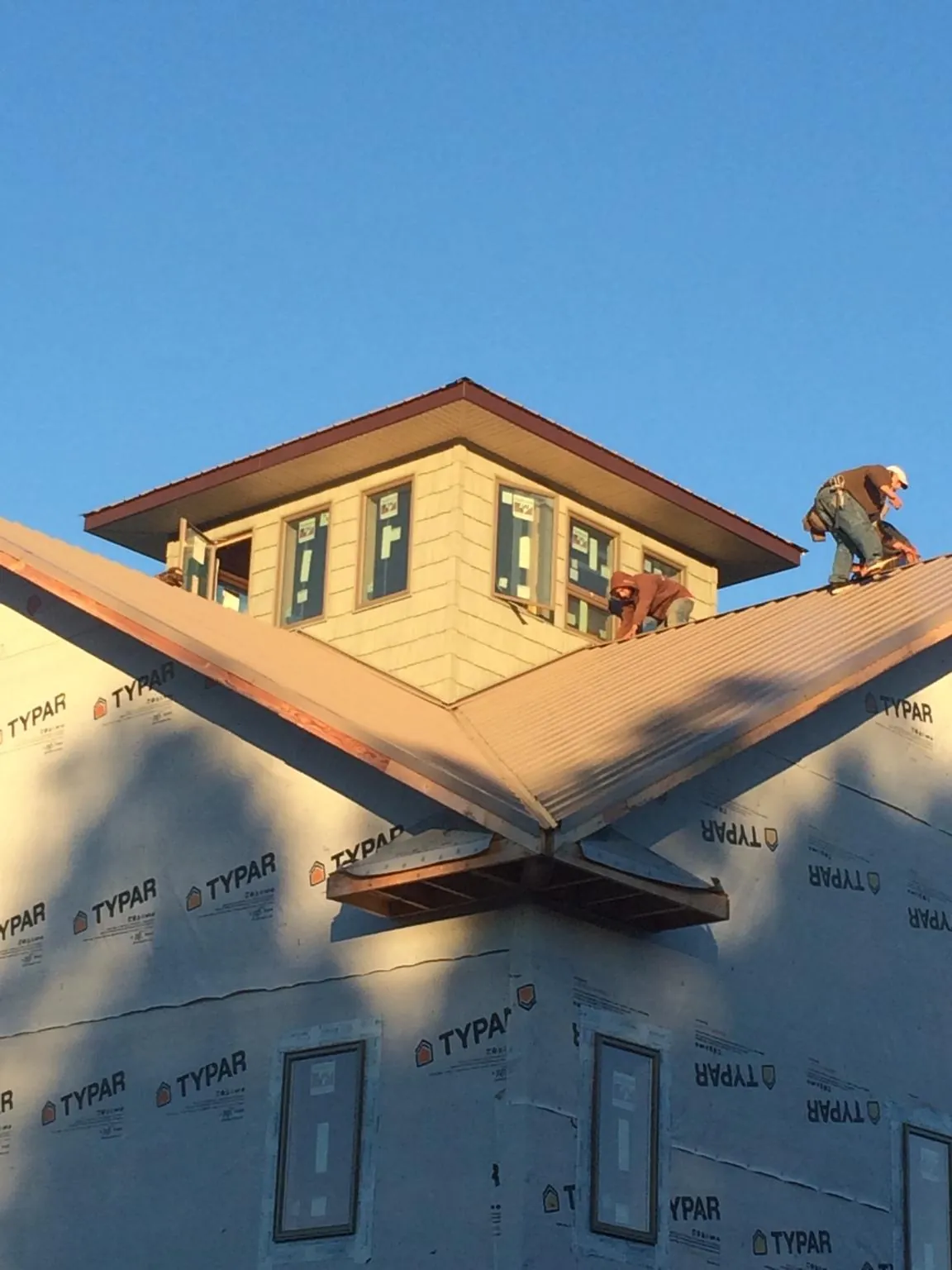 Roofers working around a rooftop cupola on a new metal roof at sunset — Roof Waterproofing in Morse by Roofing Brothers